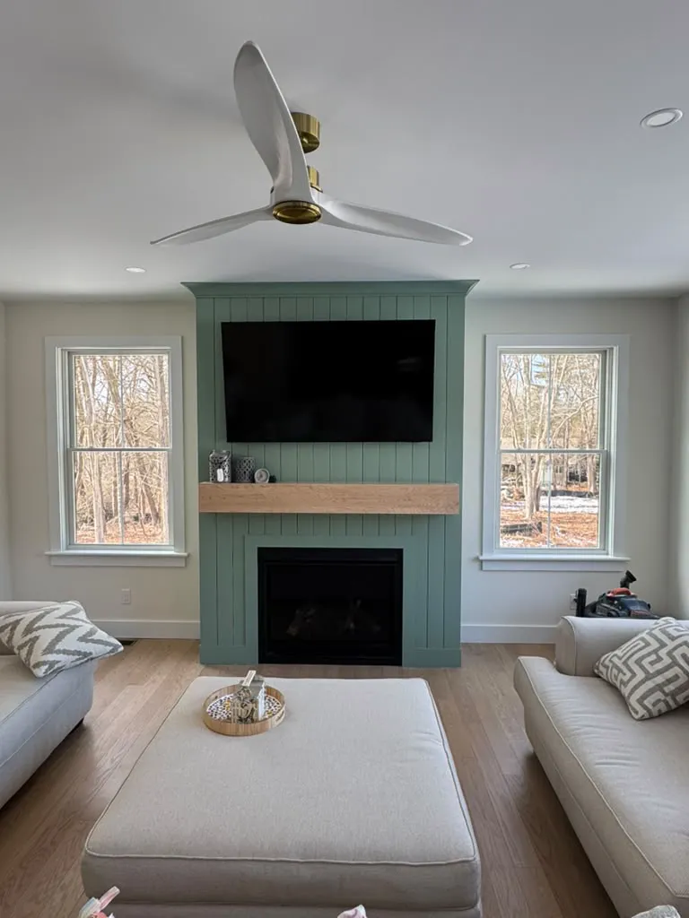 Living room with green shiplap fireplace wall and wood mantel