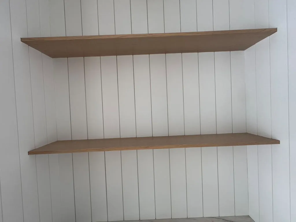 Wood floating shelves on a white shiplap wall