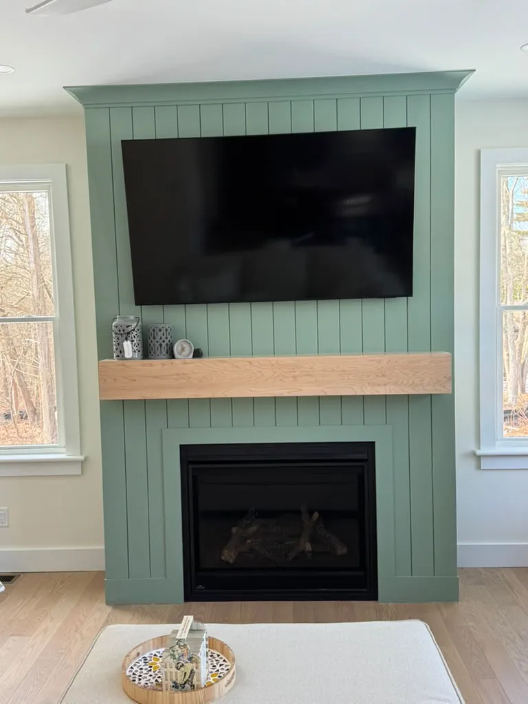 Green shiplap fireplace with TV and wood mantel